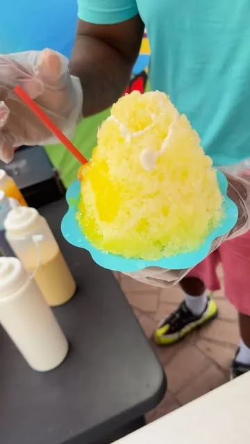 A yellow snow cone served on a blue tray